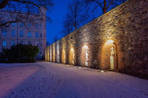 Illuminated arches with statues, historic city wall in the garden of the Moellenvogtei, dusk with snow cover on the ground, Magdeburg, Saxony-Anhalt, Germany, Europe