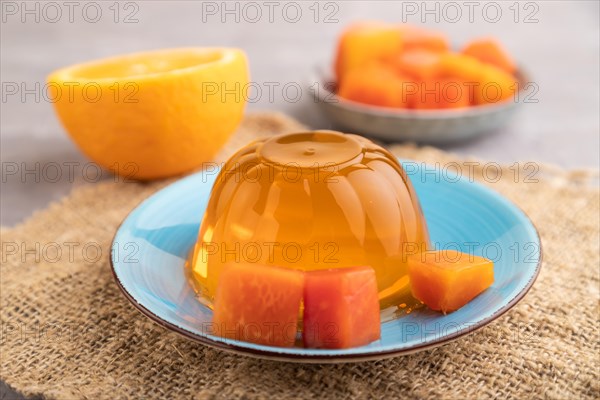 Papaya and orange jelly on gray concrete background and linen textile. side view, close up, selective focus