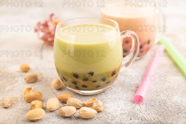 Bubble tea with pistachio and caramel in glass on brown concrete background. Healthy drink concept. Side view, close up, selective focus