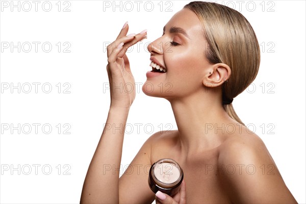 Beauty portrait of model with natural make-up holding a jar of cream. Fashion shiny highlighter on skin, sexy gloss lips make-up High quality photo