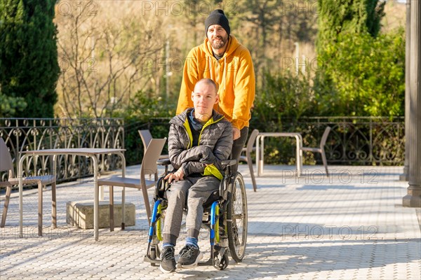 Relaxed disabled man with wheelchair and friends strolling in an urban park