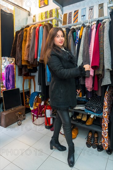 Stylish woman looking at clothes on sale in a rack in store