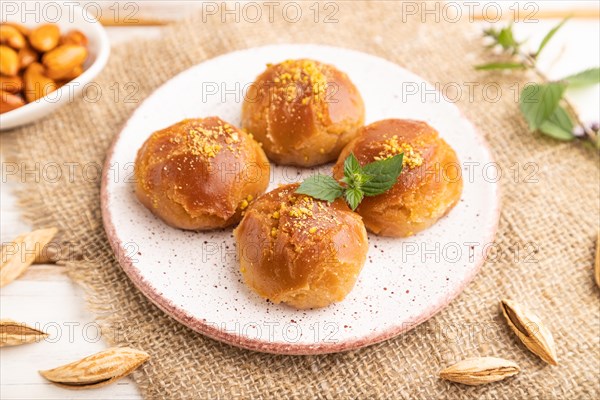 Homemade traditional turkish dessert sekerpare with almonds and honey, cup of green tea on white wooden background and linen textile. side view, close up, selective focus