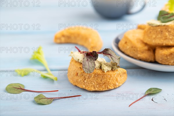 Homemade salted crescent-shaped cheese cookies, cup of coffee on blue wooden background. side view, selective focus