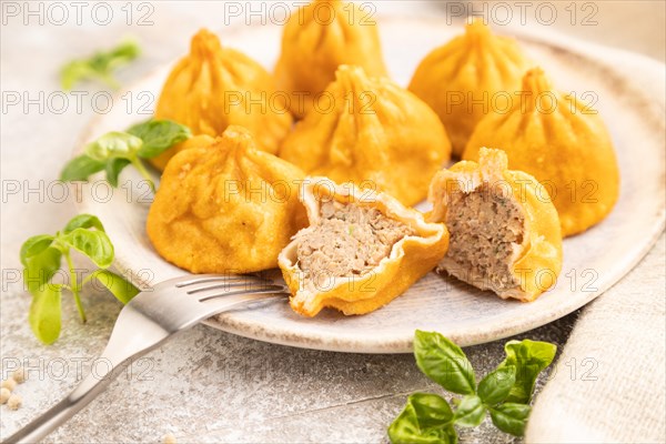 Fried manti dumplings with pepper, basil on gray concrete background and linen textile. Side view, close up, selective focus