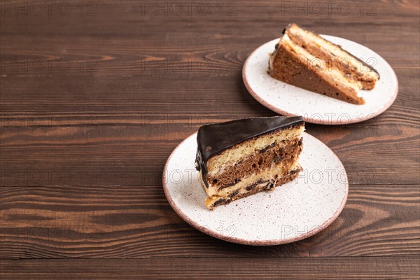 Chocolate biscuit cake with caramel cream on brown wooden background. side view, copy space