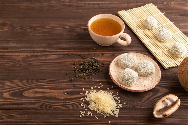 Japanese rice sweet buns mochi filled with pandan and coconut jam and cup of green tea on brown wooden background. side view, copy space
