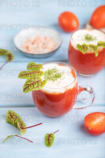 Tomato juice with sorrel, himalayan salt and sour cream in glass on blue wooden background with linen textile. Healthy drink concept. Side view, close up, selective focus
