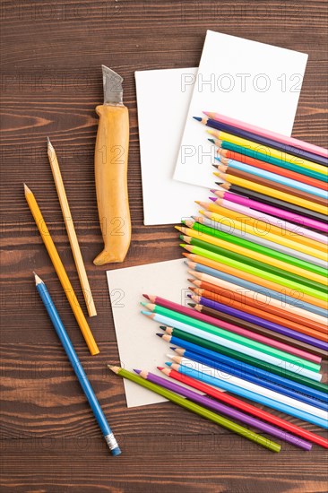 Set of watercolor pencils on brown wooden background. Top view, flat lay, close up