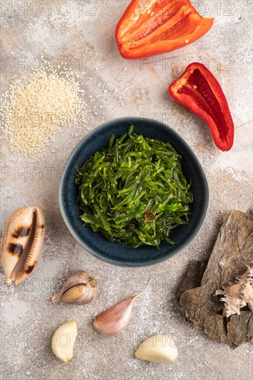 Chuka seaweed salad in blue ceramic bowl on brown concrete background. Top view, flat lay