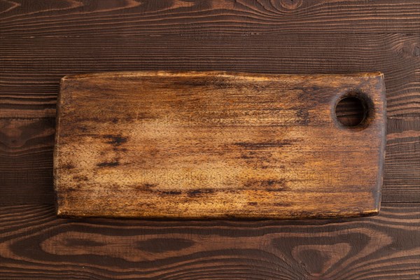 Empty rectangular wooden cutting board on brown wooden background. Top view, close up, flat lay