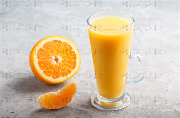 Glass of orange juice on a gray concrete background. Morninig, spring, healthy drink concept. Side view, close up
