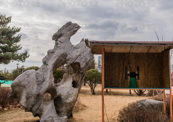 Large geological stone formation next to wooden structure at public park on cloudy winter day in South Korea