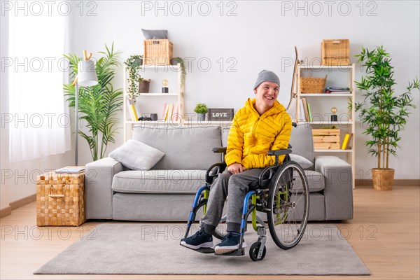 Portrait with copy space of a happy disabled man in warm clothes using wheelchair in the living room