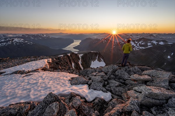 View of mountains and fjord Faleidfjorden, sun star at sunset, mountaineer at the summit of Skala, Loen, Norway, Europe