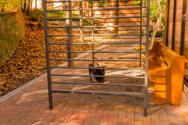 Dirty, littered public smoking area with wooden bench and ash can