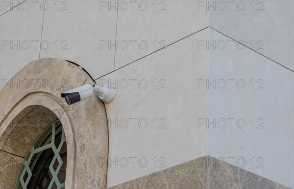 Closed circuit TV camera beside window frame of marble walled building in Istanbul, Tuerkiye