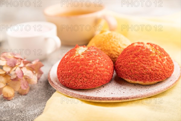 Traditional french custard dessert shu cake and cup of green tea on brown concrete background and yellow linen textile. side view, selective focus. Breakfast, morning, concept