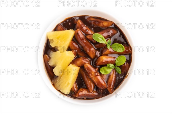 Tteokbokki or Topokki, fried rice cake stick, popular Korean street food with spicy jjajang sauce and pineapple isolated on white background. Top view, flat lay