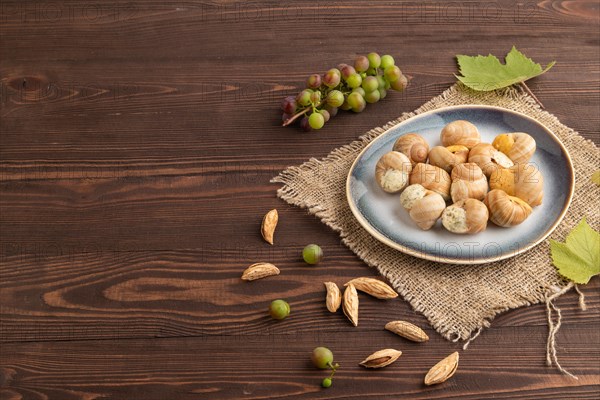 Grape (Burgundy) snails with butter and cheese on brown wooden background and linen textile. Side view, copy space