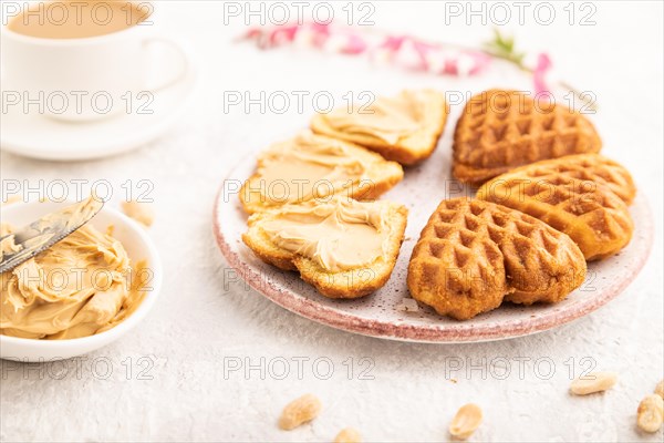 Homemade waffle with peanut butter and cup of coffee on a gray concrete background. side view, close up, selective focus