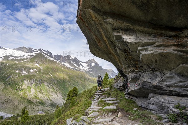 Mountaineer on a hiking trail under a rocky outcrop in a picturesque mountain landscape, Berliner Hoehenweg, Zillertal Alps, Tyrol, Austria, Europe