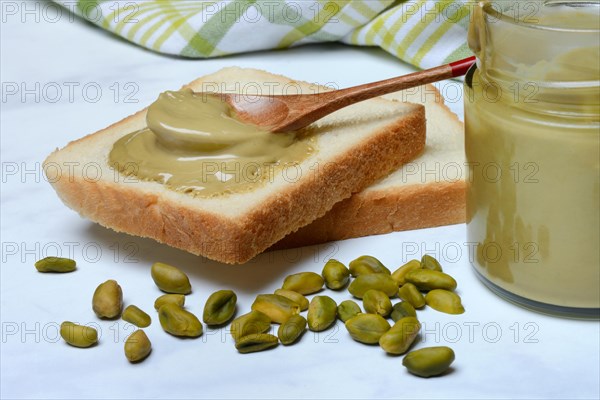 Pistachio cream with spoon on slices of bread, pistachio