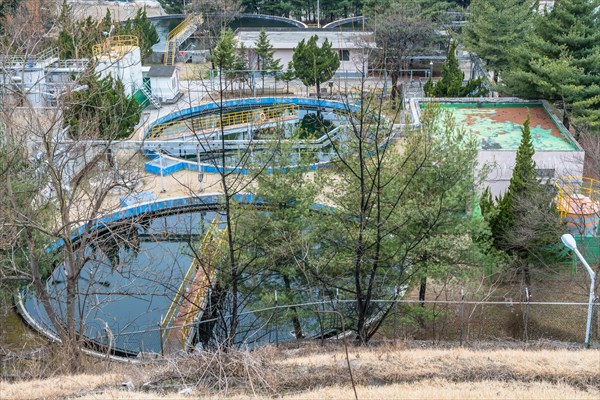 Water treatment plant with pools of water nestled among trees in rural setting. Shot from hill overlooking plant site