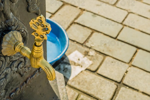 Closeup of brass faucet on public water fountain in urban park on Princess Island in Turkey