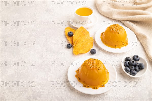 Mango and passion fruit jelly with blueberry on gray concrete background and linen textile. side view, copy space