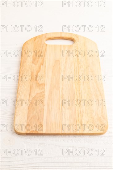 Empty rectangular wooden cutting board on white wooden background. Side view, close up