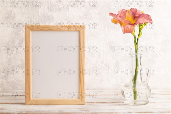 Wooden frame with purple day-lily flowers in glass vase on gray concrete background. side view, copy space, still life, mockup, template, spring, summer concept