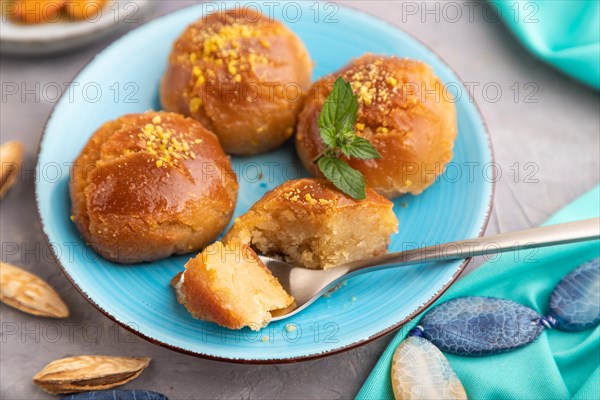 Homemade traditional turkish dessert sekerpare with almonds and honey, cup of green tea on gray concrete background and blue textile. side view, selective focus