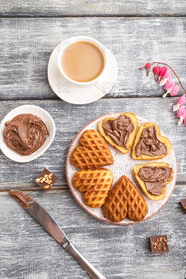 Homemade waffle with chocolate butter and cup of coffee on a gray wooden background. top view, flat lay, close up