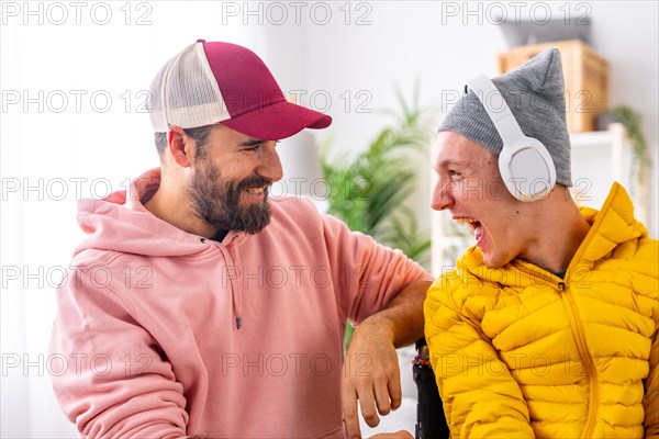 Excited disabled man listening to music using headphones with friend at home