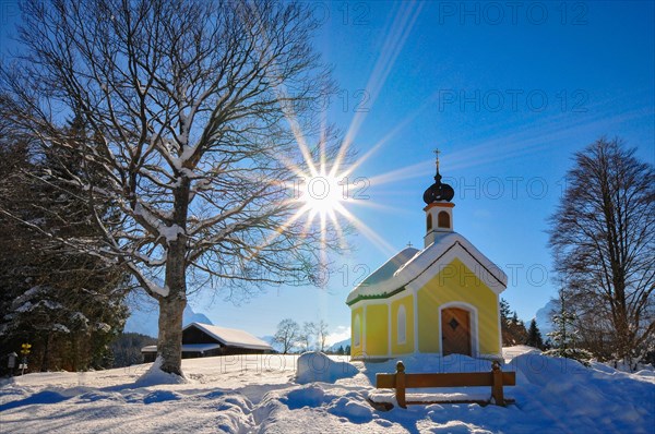 Backlit photograph of the snow-covered chapel Maria auf den Buckelwiesen in the Werdenfelser Land near Garmisch in a wintry idyll, Bavaria, Germany, Europe