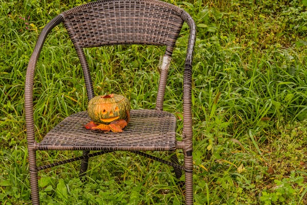 Jack-O-Lantern with leaves on chair in public park in South Korea