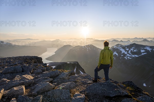 View of mountains and fjord Faleidfjorden, sun star at sunset, mountaineer at the summit of Skala, Loen, Norway, Europe