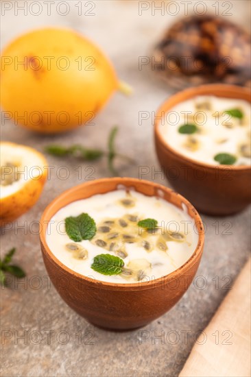 Yoghurt with granadilla and mint in clay bowl on brown concrete background and orange linen textile. side view, close up, selective focus