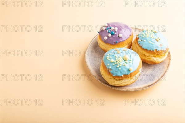 Purple and blue glazed donut on orange pastel background. side view, copy space. Breakfast, morning, concept