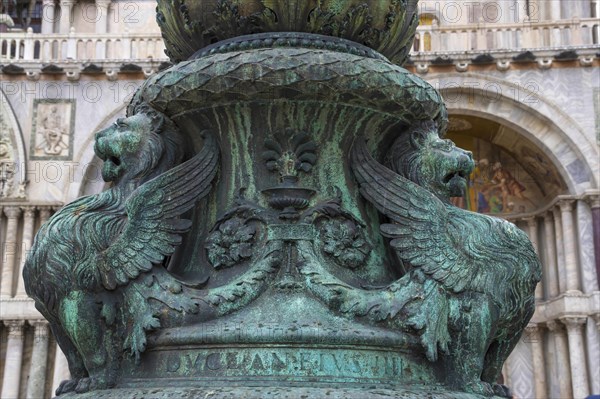 Old street ornament with winged lions and San Marco Basilica in the background, in St. Mark Square, famous tourist attraction in Venice, Italy. Selective focus