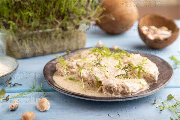 Stewed chicken fillets with coconut milk sauce and mizuna cabbage microgreen on blue wooden background. side view, close up, selective focus