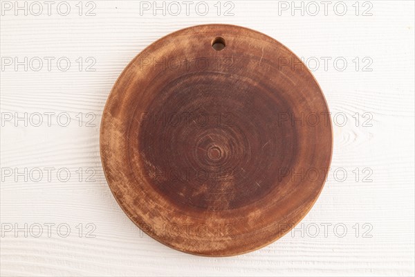 Empty round wooden cutting board on white wooden background. Top view, close up, flat lay