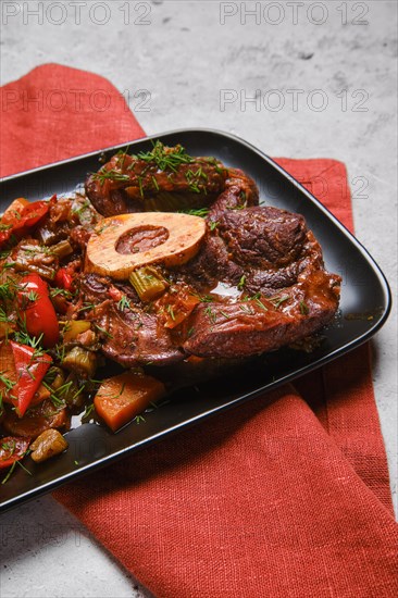 Close up view of beef ossobuco and chopped vegetables in plate