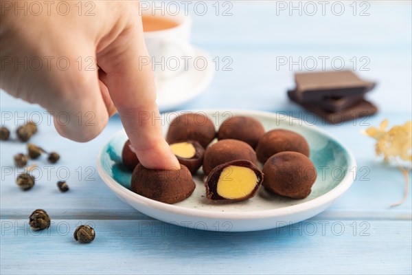 Japanese rice sweet buns chocolate mochi filled with cream and cup of green tea with hand on blue wooden background. side view, close up, selective focus