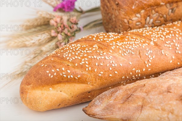 Different kinds of fresh baked bread on a white wooden background. side view, close up