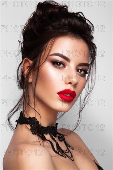 Gorgeous Young Brunette Woman face portrait. Beauty Model Girl with bright eyebrows, perfect make-up, red lips, touching her face. Sexy lady makeup for party