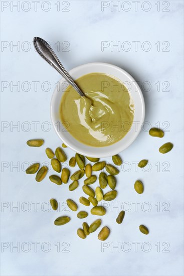 Pistachio cream in small bowls with spoon, pistachios