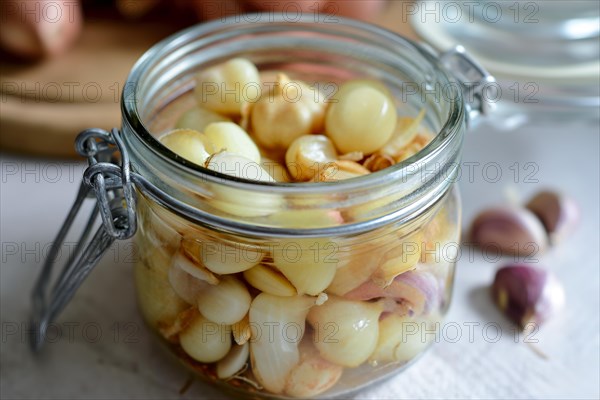 An open preserving jar full of pickled shallots and garlic cloves on a table, AI generated, AI generated