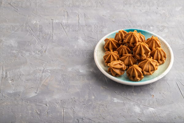Homemade soft caramel fudge candies on blue plate on gray concrete background. side view, copy space